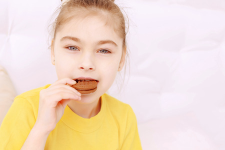 Taste good. Pretty little girl excited eating cookie on white backgroundの写真素材