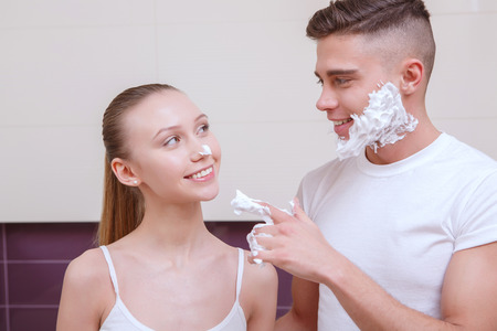 Have fun. Young man sharing his shaving gel with his girlfriend.の写真素材