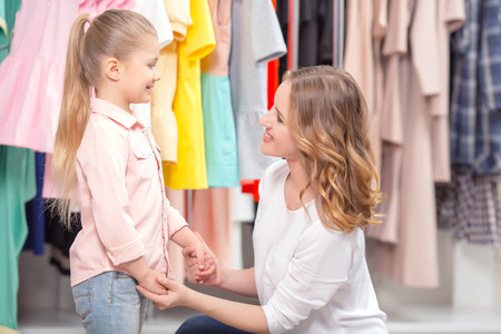 Discussing shopping. Young mother discussing shopping with her small daughter sitting in a fashion boutiqueの写真素材
