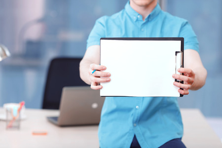 Let me show you. Businessman sitting on desk and holding folder with papers and pencil.