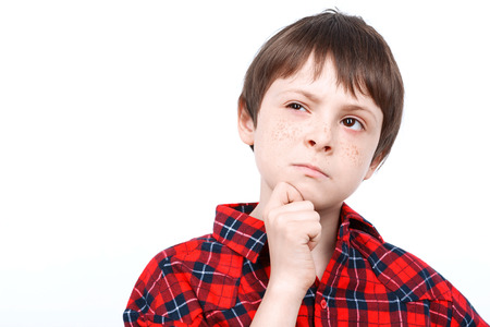 Portrait of a small boy thinking of something wearing checkered shirt close up isolated on white backgroundの写真素材