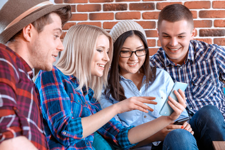 Look what I found. Beautiful young blond girl shoving something funny on her smartphone and her...
