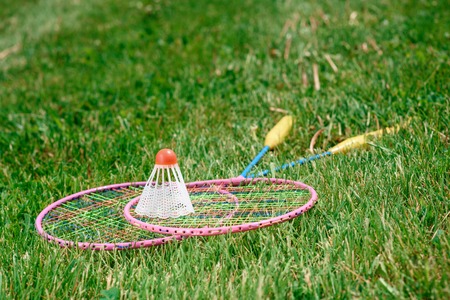 Active vacation. Picture of two badminton racquets lying on the green grass and a shuttlecock on themの写真素材