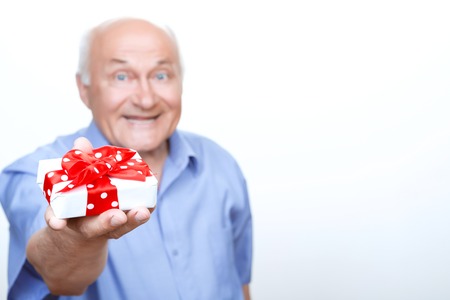 Happy Birthday. Pleasant grandfather holding the present in his hands and giving it while congratulating.の写真素材