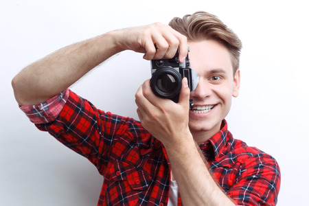 Crack a smile. Pleasant guy holding the camera in his hands while taking photos and expressing...