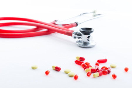Take pills. Close up of pills spread over the table with stethoscope lying on background.の写真素材