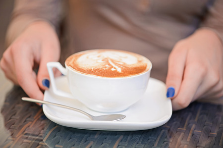 Close up portrait of freshly made cup with coffee drink held by womanの写真素材