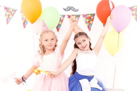 Little princesses. Two beautiful little girls happily dancing during birthday party.の写真素材