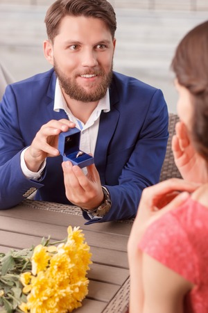 Will you marry me. Handsome boyfriend doing proposal to his pretty girlfriend in restaurant.