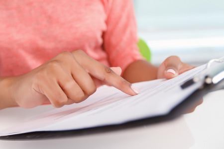 Careful work. Close p portrait of woman holding folder with papers and pointing on them with her index fingerの写真素材