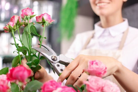 Dedicated to job. Nice upbeat  charming female florist holding garden scissors and smiling while...