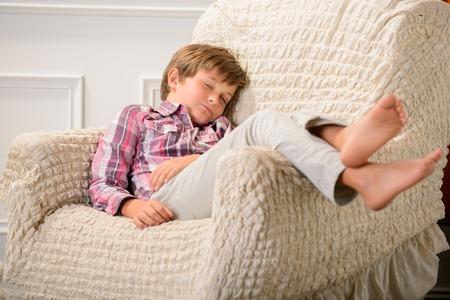 Sweet dreams. Nice little boy lying in the armchair and relaxing while sleepingの写真素材