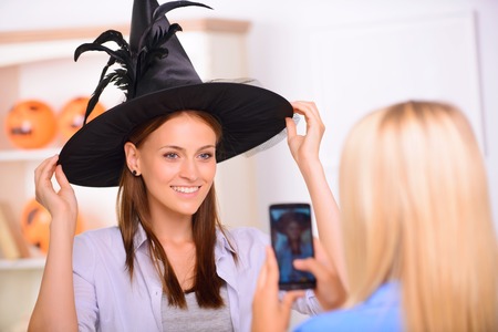 Say cheese. Nice positive beautiful girl touching her hat and having Halloween party while posing in front of the cameraの写真素材