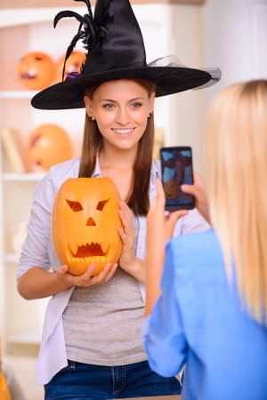 My favorite holiday. Contented charming young girl holding pumpkin and expressing positivity while posing for the photo.の写真素材