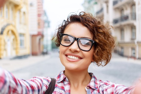 Young and beautiful. Elated pretty girl making selfie while having a walk around the cityの写真素材