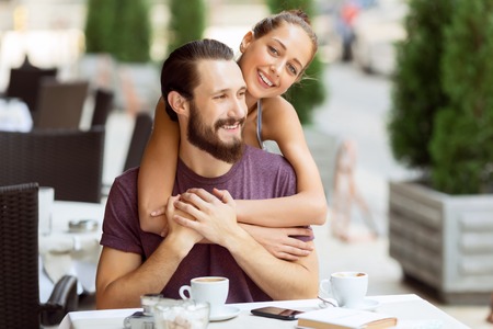 Fervant love. Pleasant overjoyed young couple sitting in the cafe and embracing while having great timeの写真素材