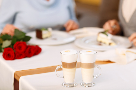 Pleasant aroma. Selective focus of coffee standing on the table with adult loving couple sitting in the backgroundの写真素材