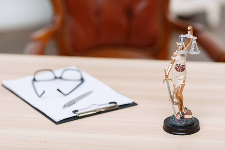 Ready to work. Folder lying on the table near little statue of justice.の写真素材