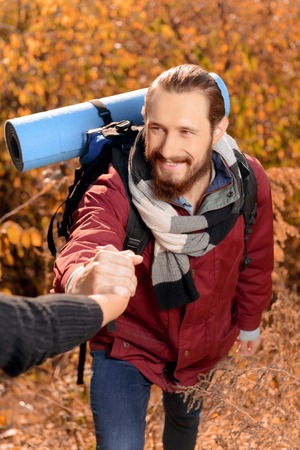 Pleasant upbeat bearded guy holding hand of his friend and smiling while travelingの写真素材