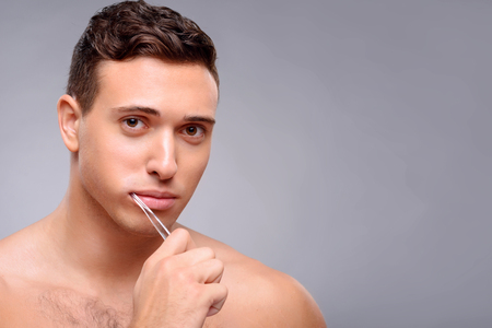 Pleasant content positive guy holding tooth brush and cleaning teeth while feeling gladの写真素材