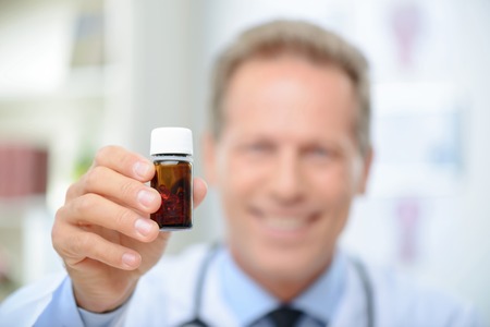 Close up of bottle of pills in hands of professional doctor holding them while being involved in workの写真素材