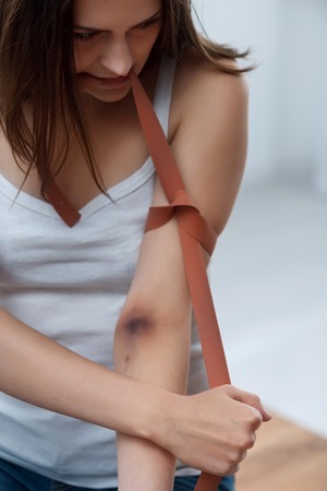 Young cheerless exhausted girl holding rope and tying her hand with it while feeling sadの写真素材