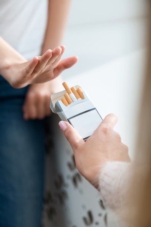 Close up of cigarettes in hands of man giving them to girl going to smokeの写真素材