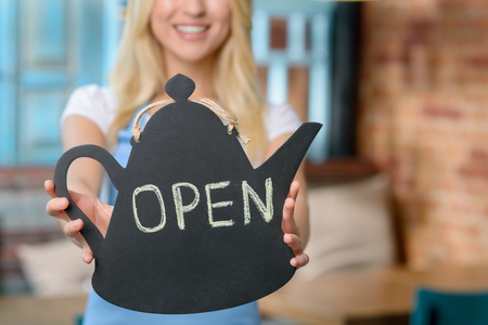 Selective focus of notice in hands of cheerful content welcoming waitress waiting for clientsの写真素材