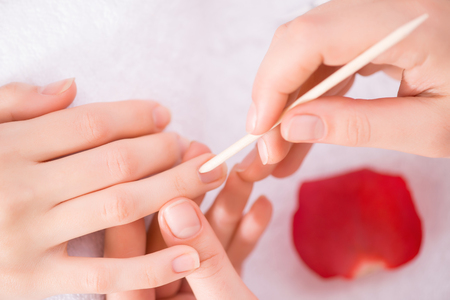 Close up of cuticle pusher in hands of professional manicurist holding it while making manicureの写真素材