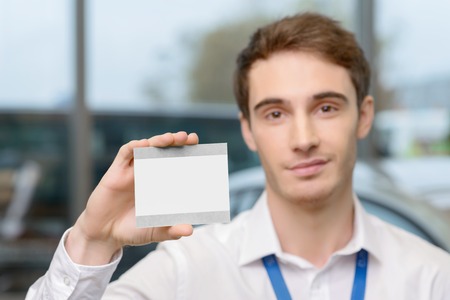 Handsome young man is showing his driving ticket after purchasing a carの写真素材