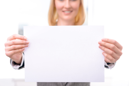 Close up of sheet of paper in hands of professional nice businesswoman holding it and expressing gladnessの写真素材