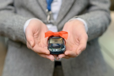 Close up of cute tiny model of car in sales lady hands.