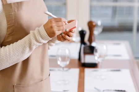 Taking order. Young attractive waitress is busy writing down latest order.の写真素材