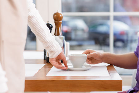 Freshly-made coffee. Waitress brings a cup of freshly made double espresso and puts it in front of the client.の写真素材