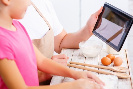 Choose the receipt.  Close up of tablet in hands of loving father  holding it and selecting what to cookの写真素材