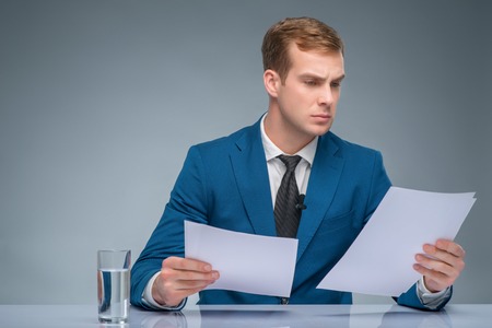 Absorbed in news. Handsome newsman looks occupied with reading important files.の写真素材