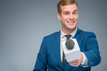 Asking questions. Smiling handsome newscaster in the process of taking an interview.の写真素材