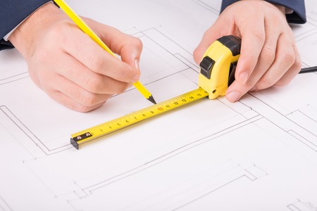 Accurate work. Male hands holding a ruler with pencil and drawing a building plan.