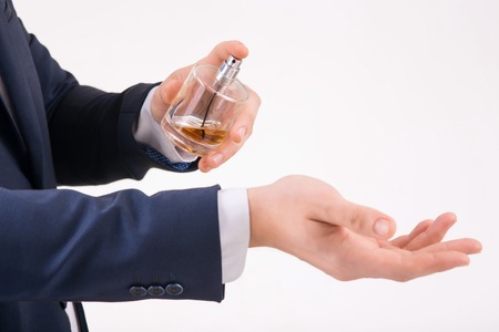 Perfume aroma. Person holding perfume with one hand and spraying it on his wrist.の写真素材