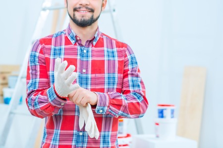 Lets work. Close up of handsome pleasant man wearing working gloves while preparing to do renovation