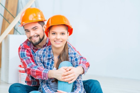 Pleasant vivacious young couple sitting on the floor and embracing while going to make renovation