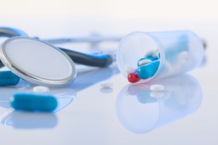 Curative pills. Bunch of colored pills and stethoscope are lying on the surface. の写真素材