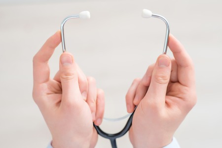 I will cure you. Close up of stethoscope in hands of professional pediatrician holding it while being involved in workの写真素材