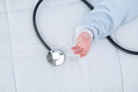 Want to play. Close up of stethoscope lying on the couch while little infant going to take itの写真素材