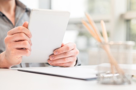 My modern adviser. Close up of tablet in hands of pleasant man holding it while sitting at the table