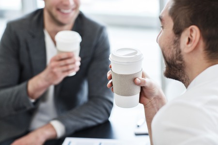 Get some rest.  Cheerful handsome  smiling nice colleagues sitting at the table and expressing positivity while drinking coffeeの写真素材