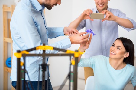 Cheerful delighted smiling student looking at the skeleton of fish printed on the 3d printer while feeling gladnessの写真素材
