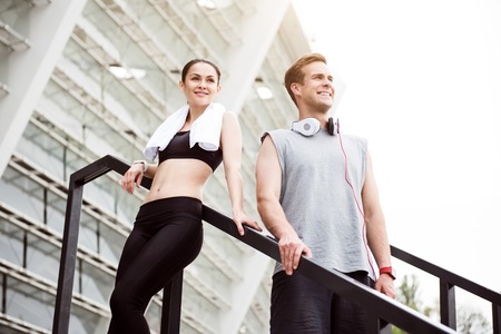 We have a rest. Tired young woman and delighted young man looking directly in front of them after a good trainingの写真素材