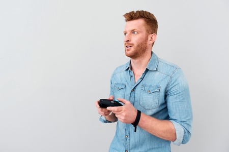 Like doing it. Cheerful involved bearded man holding game console and playing video games while...