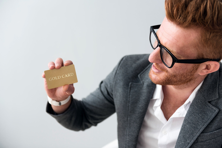 Regular customer. Positive handsome man holding card and smiling while standing isolated on grey backgroundの写真素材
